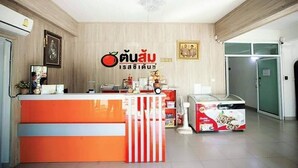 A reception area with a wooden wall, a reception desk, a chandelier, and a refrigerator. - Tonsom Residence (Uttaradit)