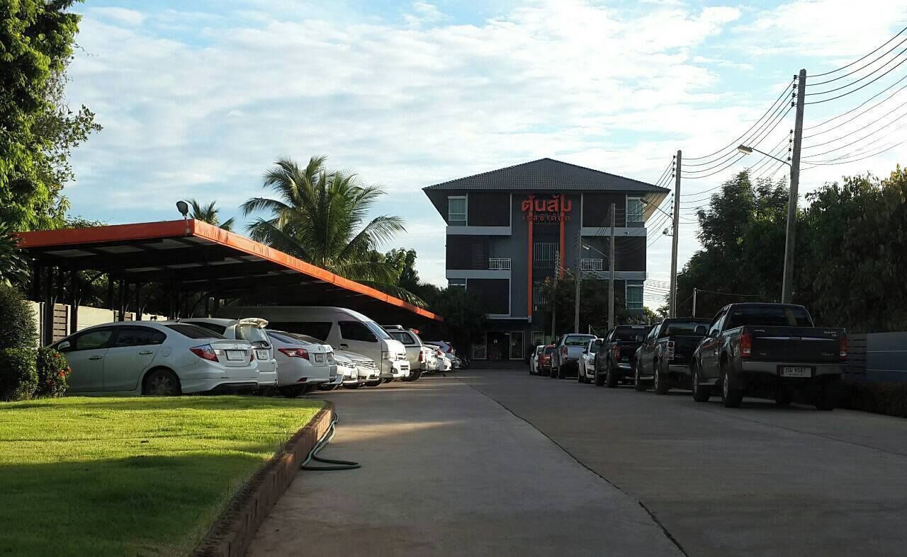 Hotel con zona de estacionamiento techada, varios coches aparcados y un edificio con un cartel.