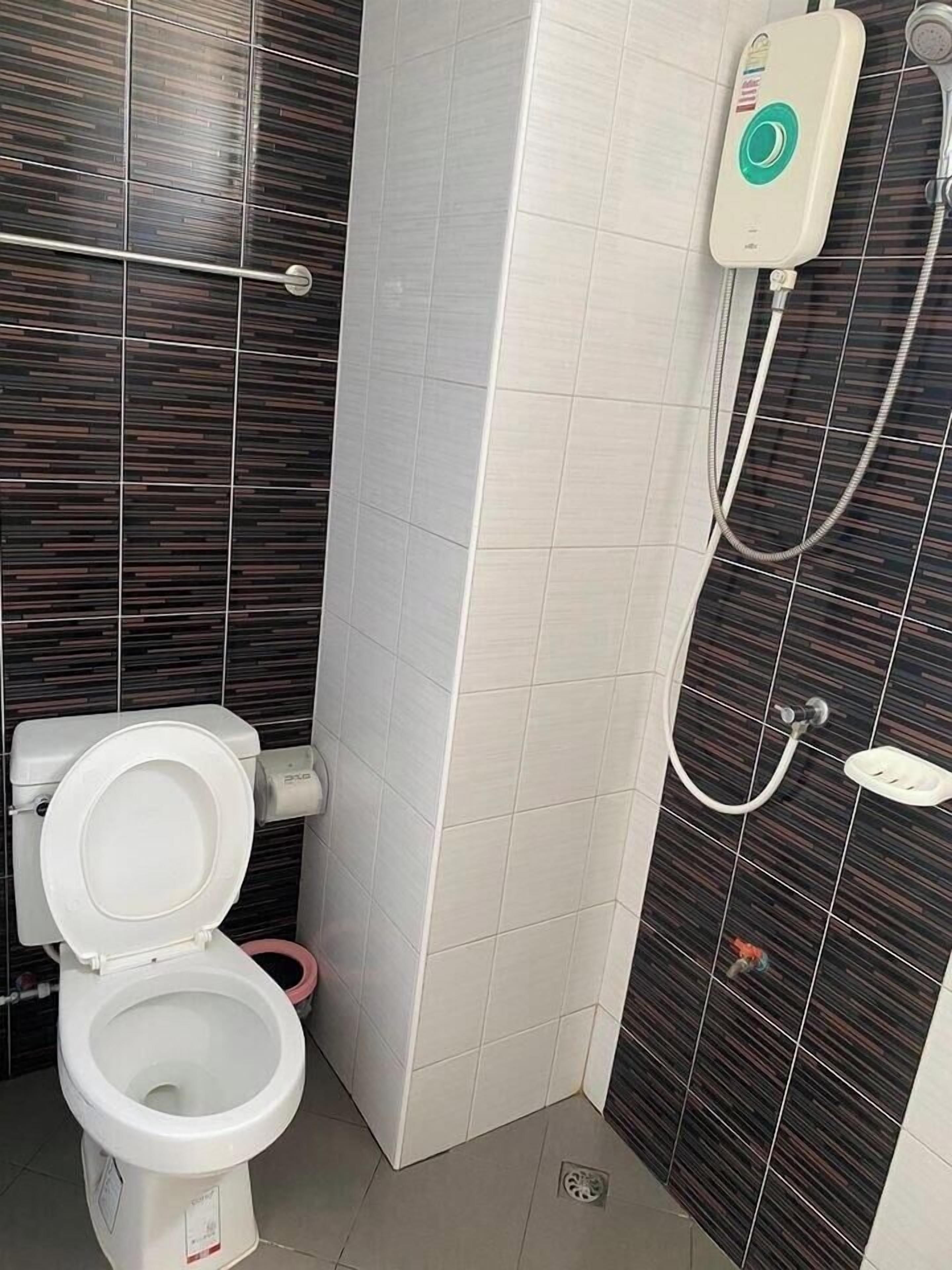 A bathroom with a toilet, a shower unit, and tiled walls.