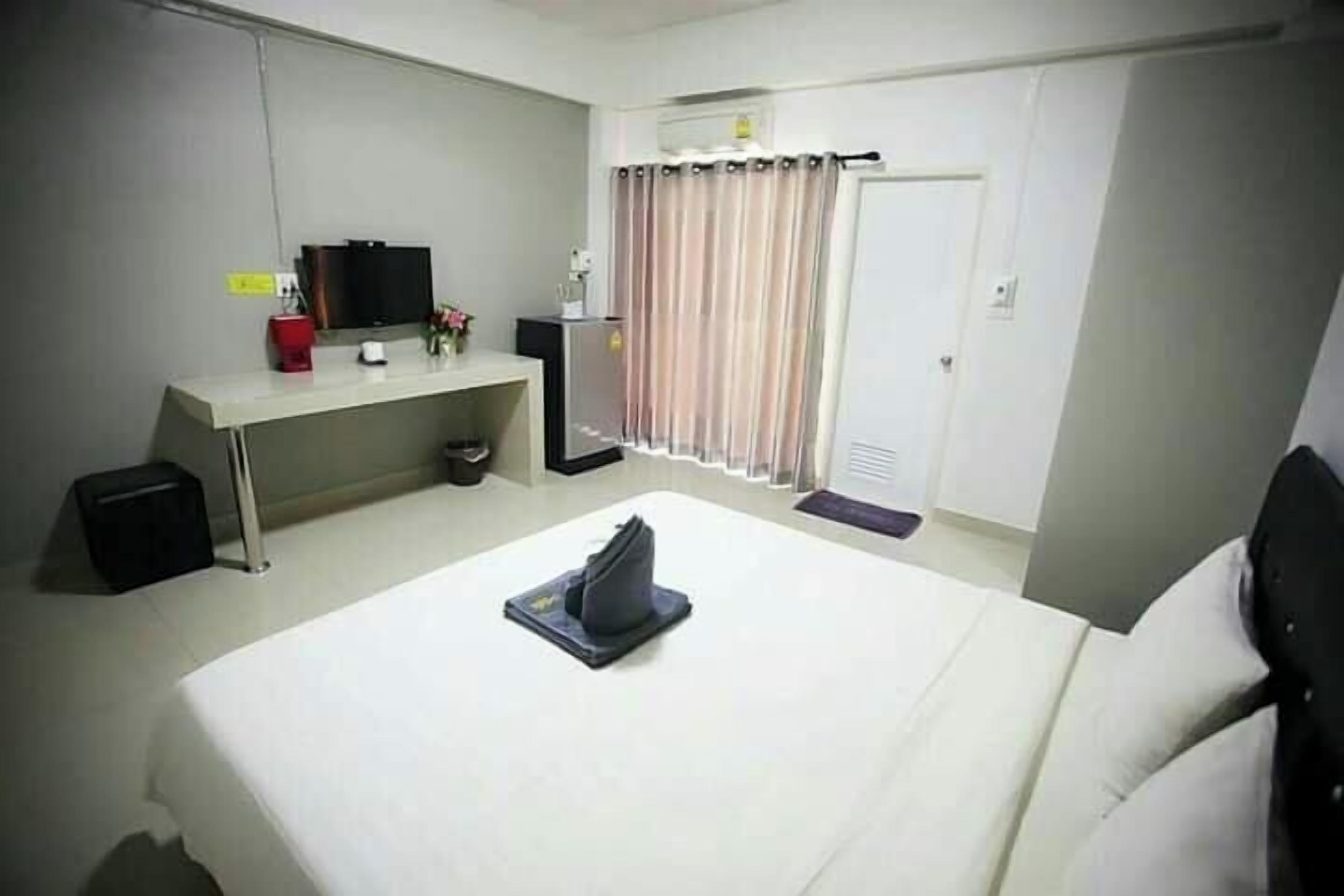 A hotel room with a bed, a desk, a television, and a curtain.