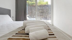 A hotel room with a bed, a striped area rug, and a view of the outside. - Apartment 'Green House' with Private Terrace, Wi-Fi and Air Conditioning (Sestri Levante)