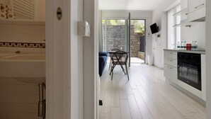 A modern kitchen with white cabinetry, a dining area with a table and chairs, and a view through an open door to a patio area. - Apartment 'Green House' with Private Terrace, Wi-Fi and Air Conditioning (Sestri Levante)