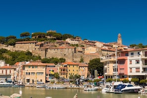 A coastal town with historic buildings, a prominent tower, and a marina with boats.
