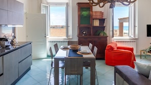 Una cocina moderna con zona de comedor, un sofá rojo y vista al mar.