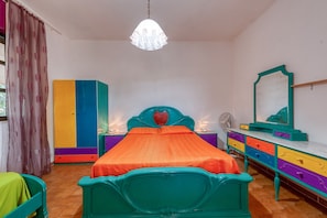 Une chambre à coucher avec un lit, une commode, un miroir et un luminaire au plafond.