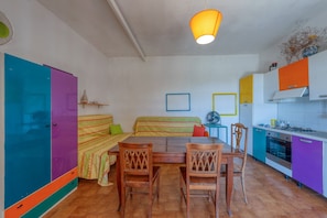Une cuisine avec une table à manger, des chaises et des armoires aux couleurs vives.