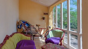 Una habitación iluminada por el sol, con un ventanal grande, una bicicleta y dos sillas.