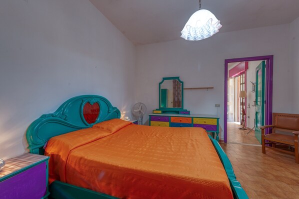 A bedroom with a bed, a dresser, a mirror, and a chair.