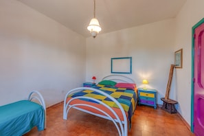 Une chambre à coucher avec un lit, une table de chevet, une lampe, une chaise et une porte.