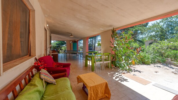 A covered outdoor seating area with a sofa, chairs, and a table.