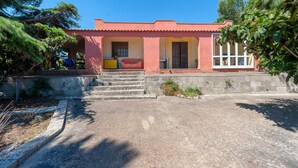 A building with a red facade, a set of concrete steps leading to a door, and a clear sky.