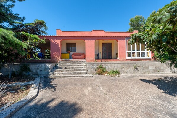 A building with a red facade, a set of concrete steps leading to a door, and a clear sky. - Holiday Home 'Sprocketlandia' with Private Terrace, Shared Garden and Wi-Fi (Frigole)