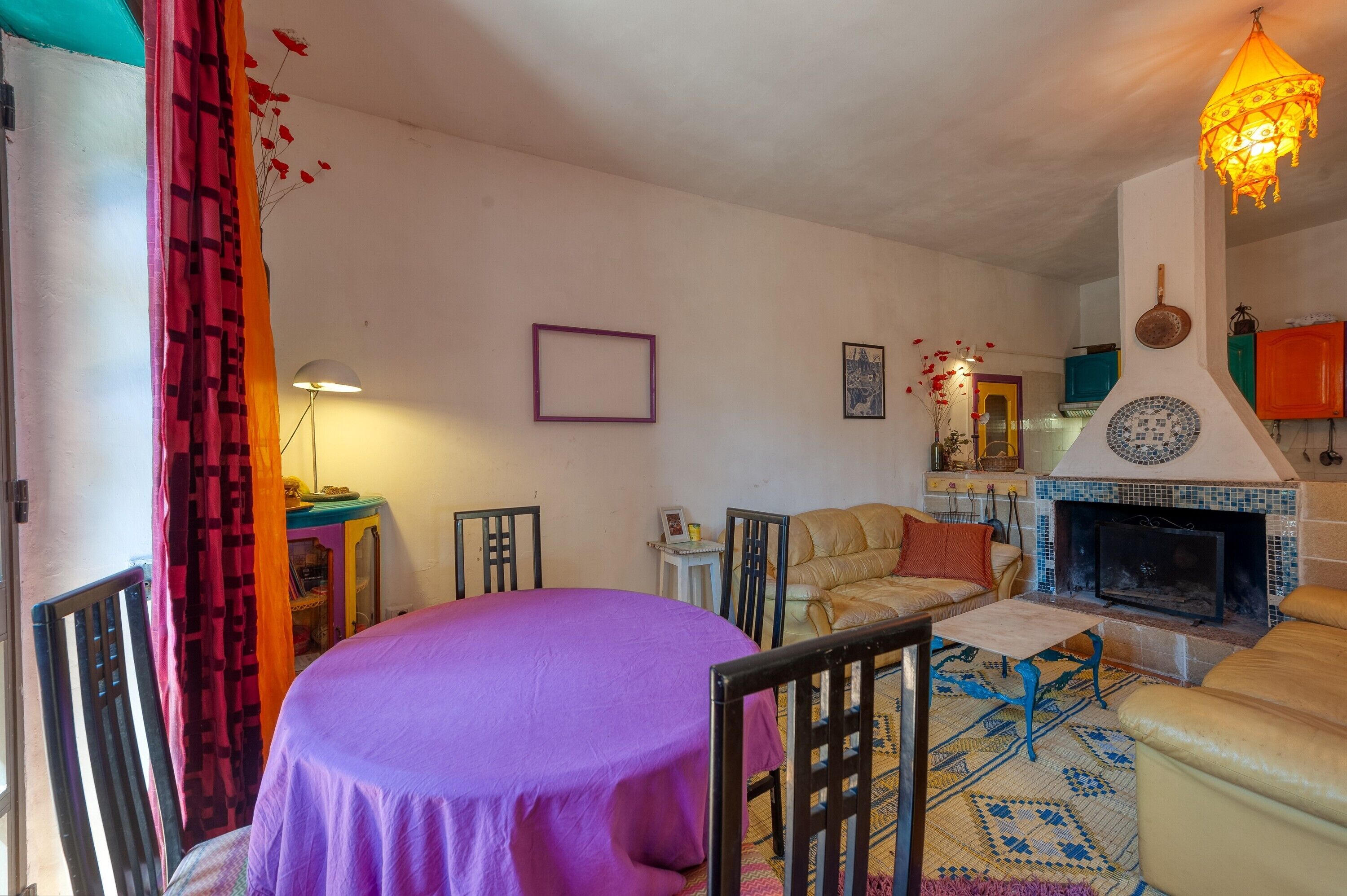 Een woonkamer met een open haard, een ronde tafel en een bank.