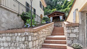 Eine Steintreppe führt zu einem Gebäude mit einer Holzpergola und einem Blumenbeet.