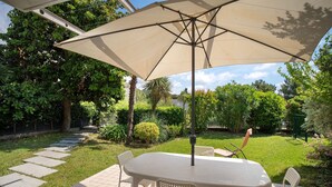 A patio with a table and chairs, surrounded by a garden with a variety of plants and a stone pathway. - Apartment 'Avocado' with Shared Pool, Wi-Fi and Air Conditioning (Diano Castello)