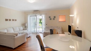 A living room with a sofa, a dining table, and a TV. - Apartment 'Avocado' with Shared Pool, Wi-Fi and Air Conditioning (Diano Castello)