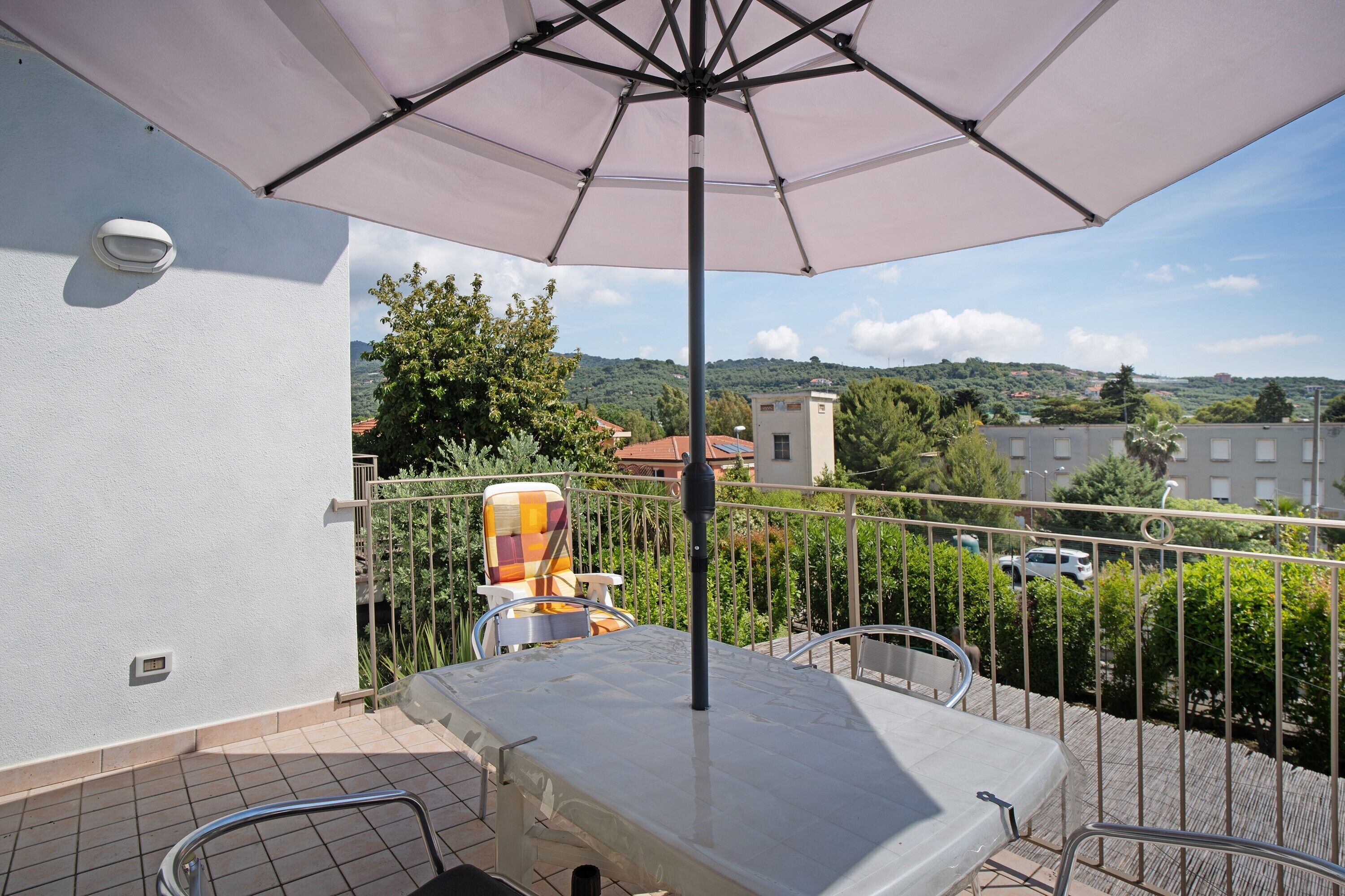A balcony with a table, chairs, and a large umbrella.