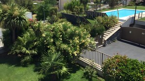 Una zona residencial con piscina, abundante vegetación y casas con tejas rojas.