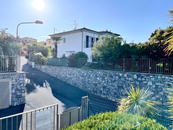 A residential street with a stone wall, a metal gate, and a clear blue sky.