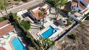 Une propriété résidentielle dotée d’une piscine, de panneaux solaires et d’un espace patio.