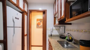 A kitchen with wooden cabinets, a built-in microwave, a granite countertop, and a sink with a faucet. - SUH Copacabana 71 Princess Beach (Rio de Janeiro)