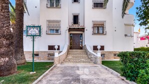 A hotel entrance with a stone staircase leading to a door, a signboard, and a well-maintained lawn. - Apartment 'El Palmar' with Sea View, Wi-Fi and Air Conditioning (Denia)