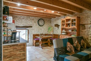 A rustic interior with a wooden table, a sofa, a cabinet, and a clock on the wall.