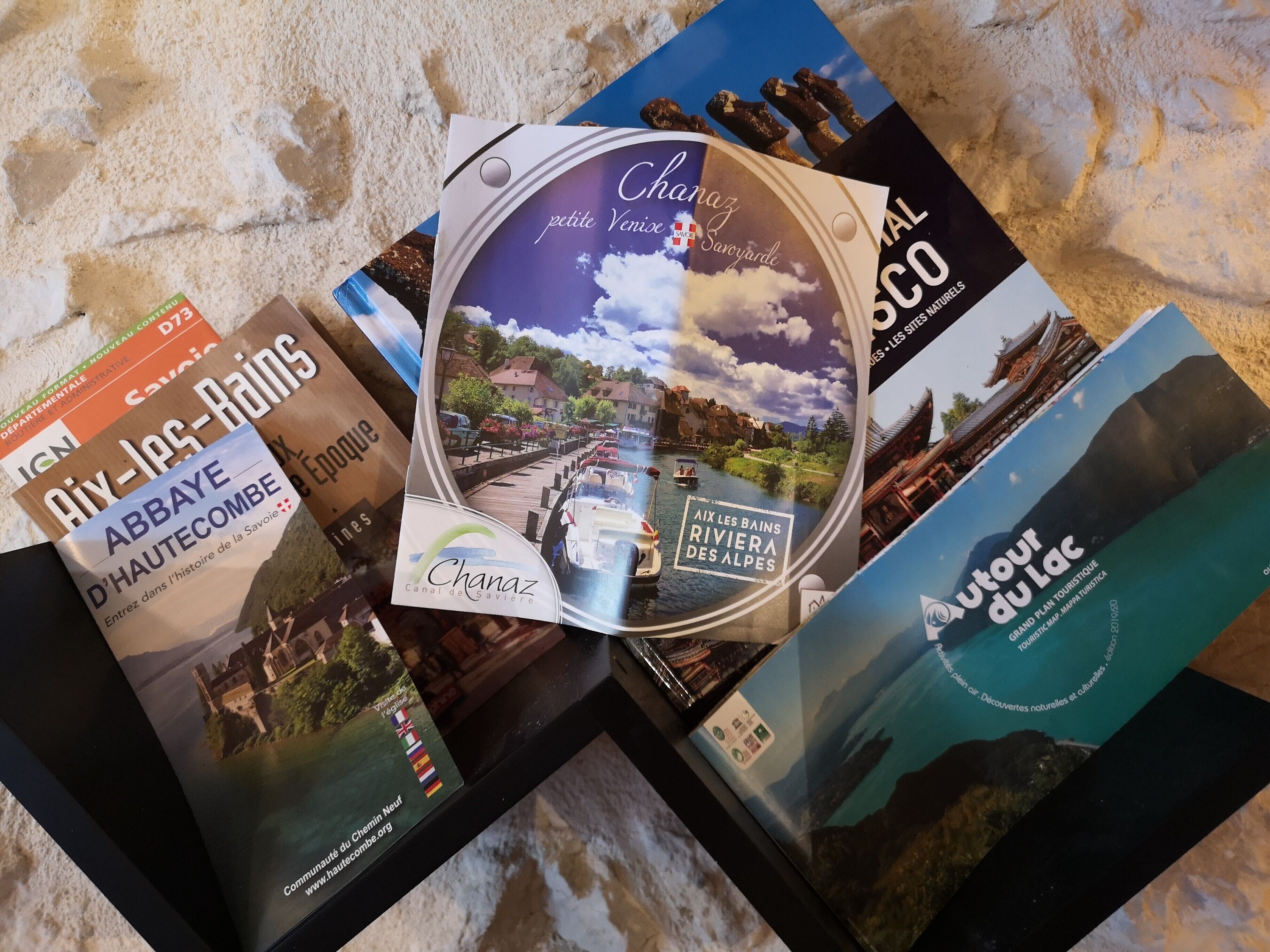 Eine Auswahl an Reisebroschüren und einer CD/DVD-Hülle mit Ansichten eines Kanals und einer Berglandschaft.