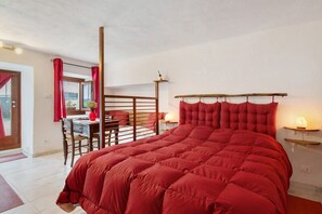 Une chambre avec un grand lit rouge, un bureau en bois et une chaise.