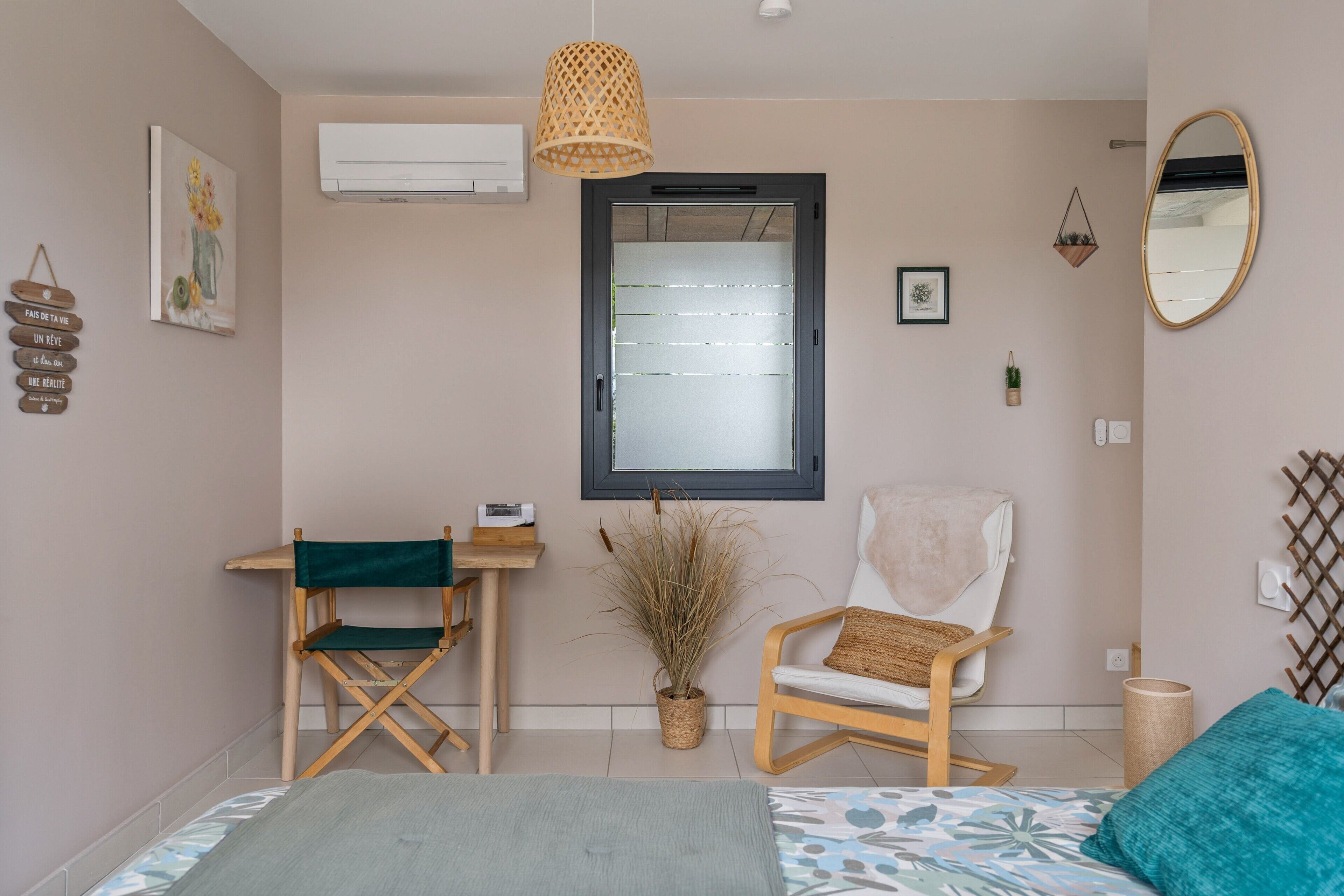 A bedroom with a bed, a chair, a desk, a hanging lamp, a window, and a mirror.