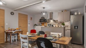 Une cuisine moderne avec un coin repas, comprenant une table en bois, des chaises et un réfrigérateur.