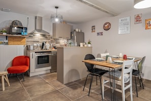 Une cuisine moderne avec un îlot central, une table à manger avec des chaises et une chaise rouge.
