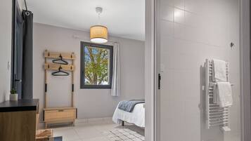A modern bathroom with a shower, a towel rack, and a window with a view of trees.