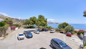 A parking lot with cars, a view of the sea, and a hilly landscape in the background. - Apartment 'Balcón Del Mar' with Sea Views, Wi-Fi and Air Conditioning (La Herradura)