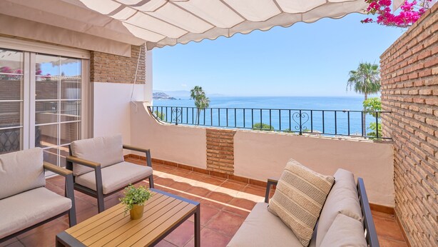 A balcony with a view of the sea, a sofa, a table, and a potted plant. - Apartment 'Balcón Del Mar' with Sea Views, Wi-Fi and Air Conditioning (La Herradura)