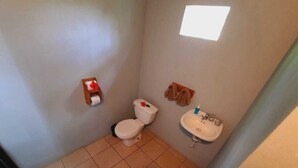 A small bathroom with a toilet, sink, and a towel rack. - corcovado green parrot (Drake Bay)