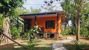 A single-story building with an orange exterior, a covered porch, and a stone pathway leading to the entrance. - corcovado green parrot (Drake Bay)