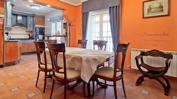 Een eetgedeelte met een ronde tafel gedekt voor vier personen, omringd door houten stoelen met comfortabele zittingen.