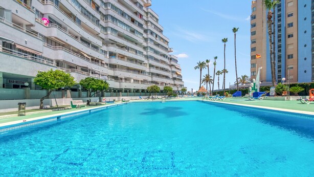 A large swimming pool with lounge chairs, a bar, and a restaurant adjacent to a multi-story hotel building. - Apartment 'Aguamarina C' with Sea View, Wi-Fi and Air Conditioning (Calpe)