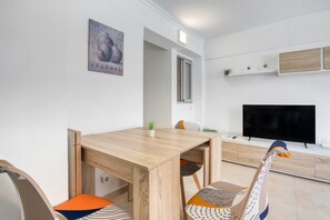 A modern living room with a wooden dining table, colorful chairs, a flat-screen TV, and a painting on the wall. - Apartment 'Aguamarina C' with Sea View, Wi-Fi and Air Conditioning (Calpe)