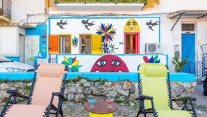 A colorful building with a mural, outdoor seating, and a stone wall. - Holiday Home 'Coscienza' with Sea View, Wi-Fi and Air Conditioning (Palermo)