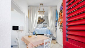 A dining area with a table, chairs, a television, and a bed with curtains. - Holiday Home 'Coscienza' with Sea View, Wi-Fi and Air Conditioning (Palermo)