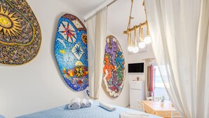 A hotel room with a bed, a desk, a TV, and artwork on the walls. - Holiday Home 'Coscienza' with Sea View, Wi-Fi and Air Conditioning (Palermo)