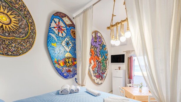 Una habitación de hotel con una cama, un escritorio, un televisor y obras de arte en las paredes.