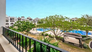 A balcony with a view of a pool area, surrounded by greenery and buildings. - Apartment 'Congrio - Resort Holiday Treat' with Mountain View, Wi-Fi and Air Conditioning (Torre-Pacheco)