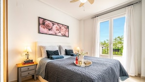 A bedroom with a bed, a nightstand, a window with curtains, and a ceiling fan. - Apartment 'Congrio - Resort Holiday Treat' with Mountain View, Wi-Fi and Air Conditioning (Torre-Pacheco)