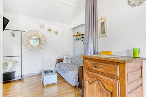 Una camera da letto con un letto, una cassettiera in legno, un tavolino, uno specchio e decorazioni a parete.