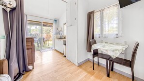 Una habitación con una mesa de comedor, sillas, un televisor y una puerta corrediza que da a un balcón.