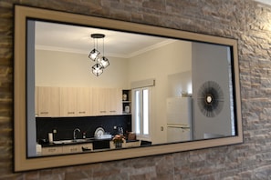 Une cuisine avec des meubles de rangement en bois, un plan de travail noir, un évier et un luminaire suspendu.