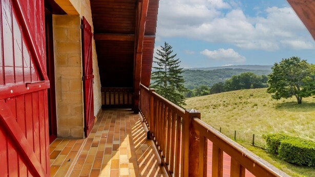 A balcony with a view of a hilly landscape.